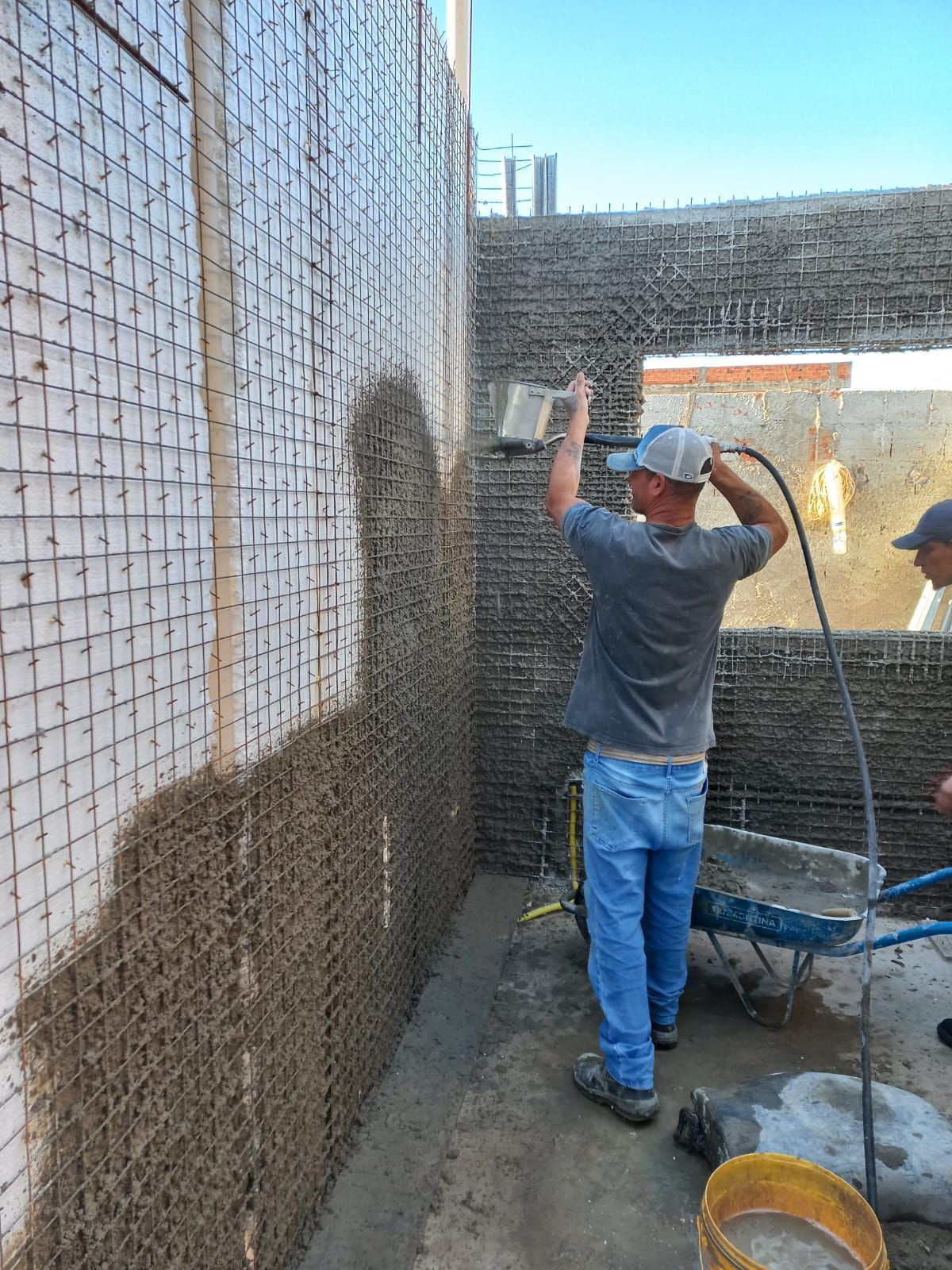 Profissional projetando argamassa em parede durante a obra