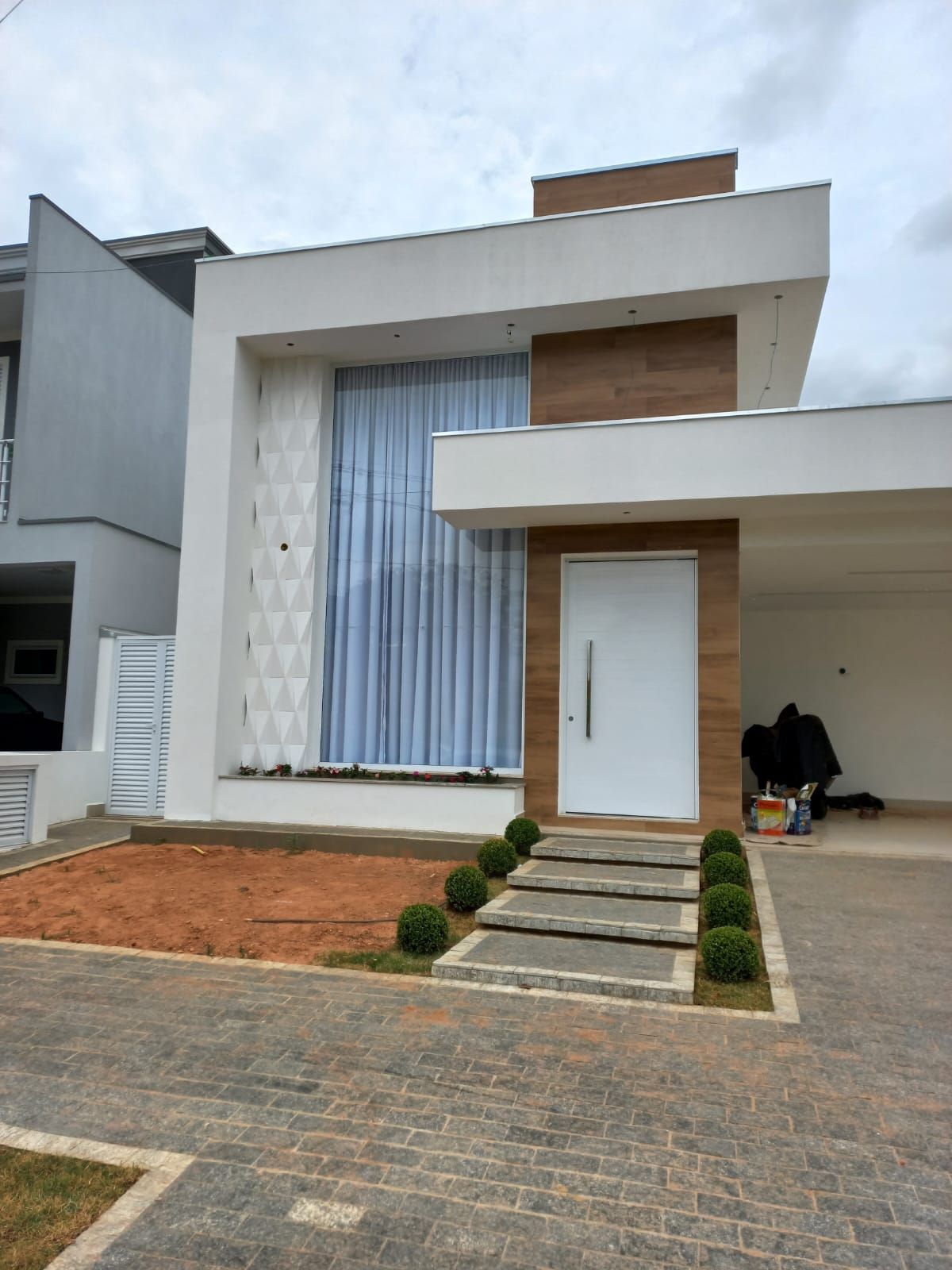 Residência entregue pela RS Construtora, fachada branca com porta pivotante